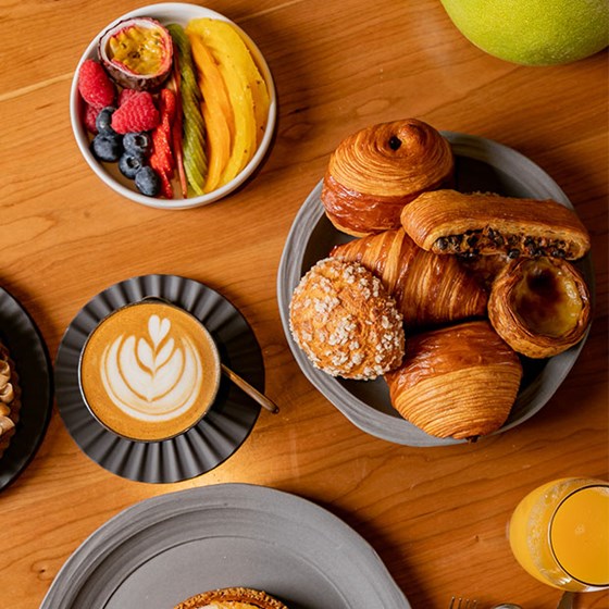 breakfast spread including bowl of pastries, sliced fruit and coffee