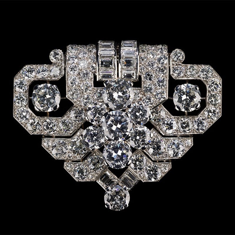 Cartier brooch shaped like a blooming rose, crafted entirely from pavé-set diamonds and baguette-cut accents, with a curved diamond-set stem.