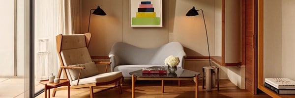 Calm, light-filled lounge at The Berkeley with a mid-century armchair, sculptural sofa, modern lamps, and coffee table with art books and flowers.