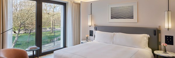 double bed in suite with doors that opening out, and a view of horses in hyde park